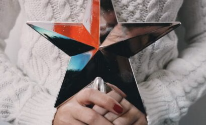 Kadın ellerinde tutulan renkli metalik yıldız, mevsim trendlerini yansıtan şık bir tatil dekoru.