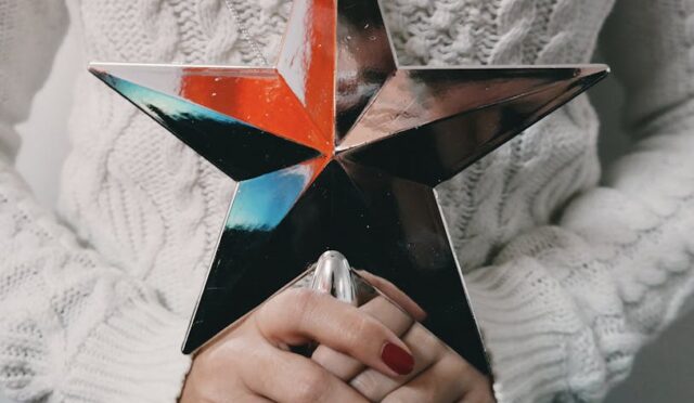 Kadın ellerinde tutulan renkli metalik yıldız, mevsim trendlerini yansıtan şık bir tatil dekoru.