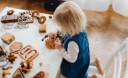 "Yüksek açıdan çekilmiş bu görselde, genç bir çocuk eğitim amaçlı ahşap oyuncaklarla puzzle oynuyor."