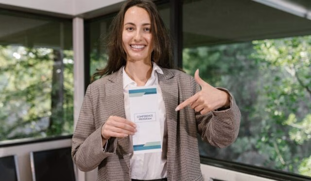 Eğitimde süreklilik konulu konferans programını gülümseyerek tutan kadın, katılımcılara ilham veriyor.